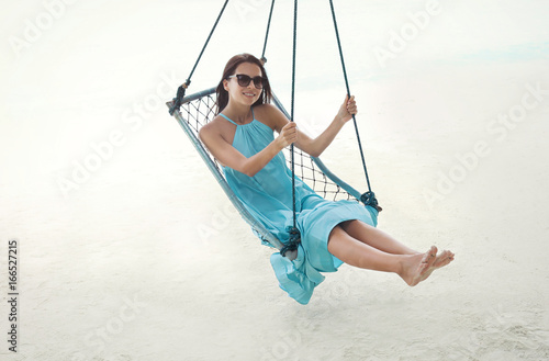 Beautiful young woman on swing at sea resort © Africa Studio