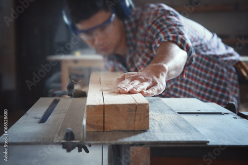 Slika na platnu Young carpenter working with circular saw in shop