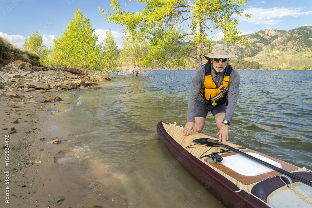 Senior paddler with expedition stand up paddleboard Senior paddler with expedition stand up paddleboard