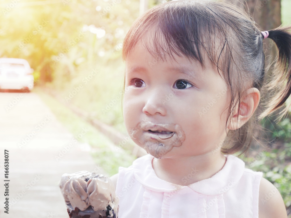 little girl eat ice cream with its mouth smeared with ice cream in park. little girl eat ice cream with its mouth smeared with ice cream in park.