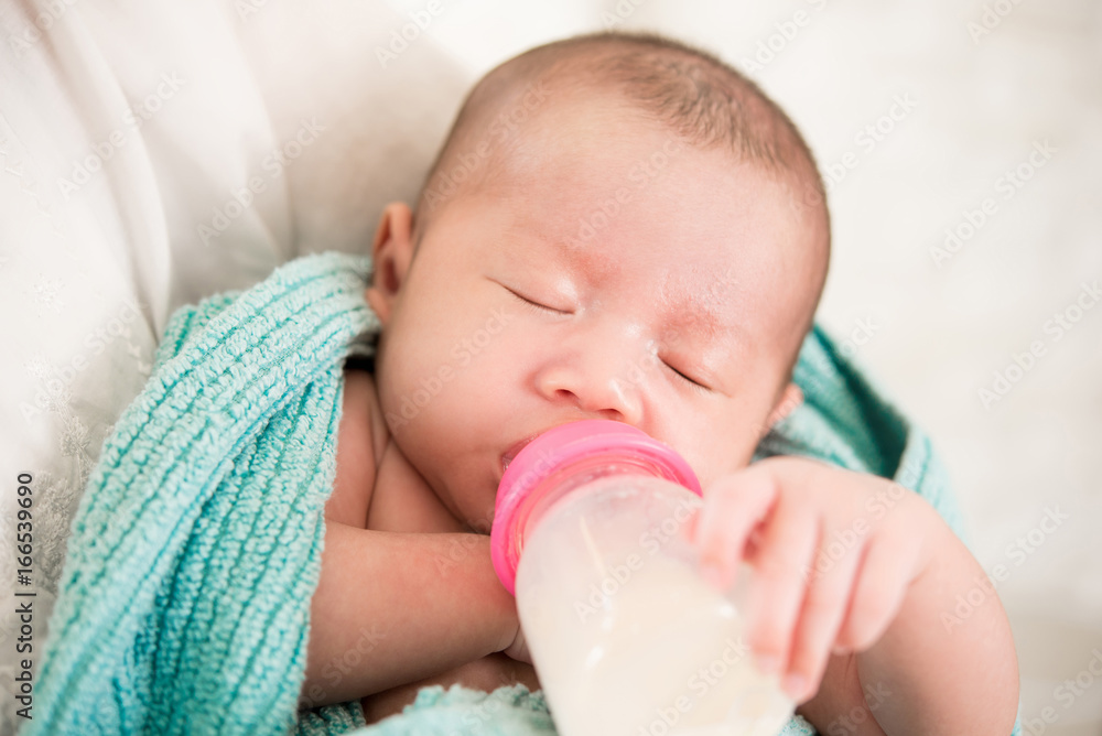 Sleepy cute newborn baby drinking milk from bottle Sleepy cute newborn baby drinking milk from bottle