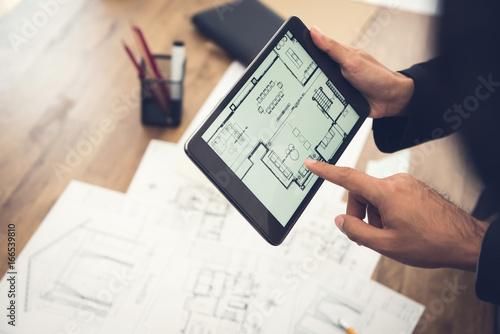 Real estate agent or architect presenting house floor plan to client on tablet computer photo