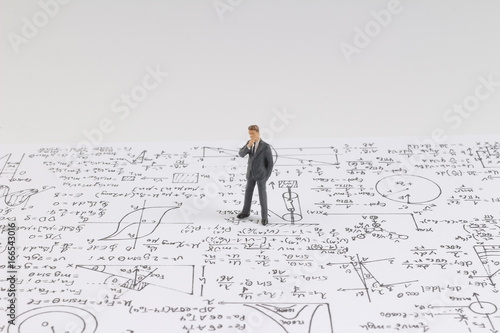 Tiny figure stands near math formula photo