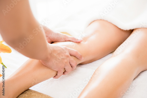Therapist giving Thai oil leg massage treatment to a woman in spa
