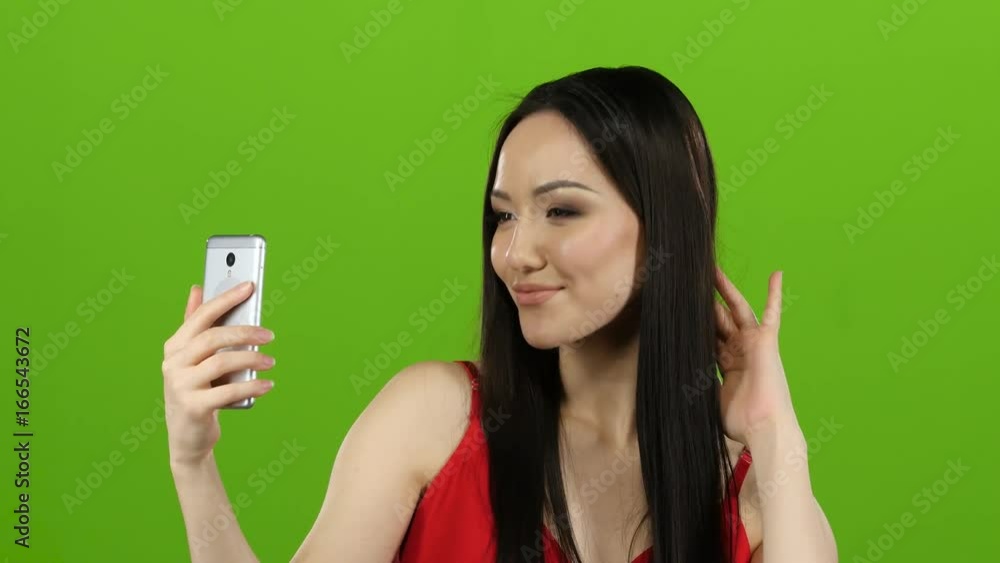 Asian girl does selfie, she smiles while looking at the camera. Green screen Asian girl does selfie, she smiles while looking at the camera. Green screen
