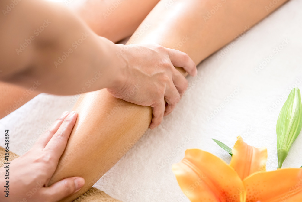Therapist giving Thai oil leg massage treatment to a woman in spa foto