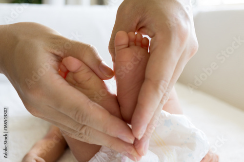 Tiny Newborn Baby's feet on female Heart Shaped hand