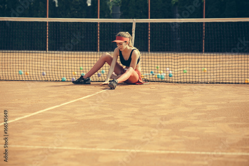 woman sitting and relax on tennis court in cap