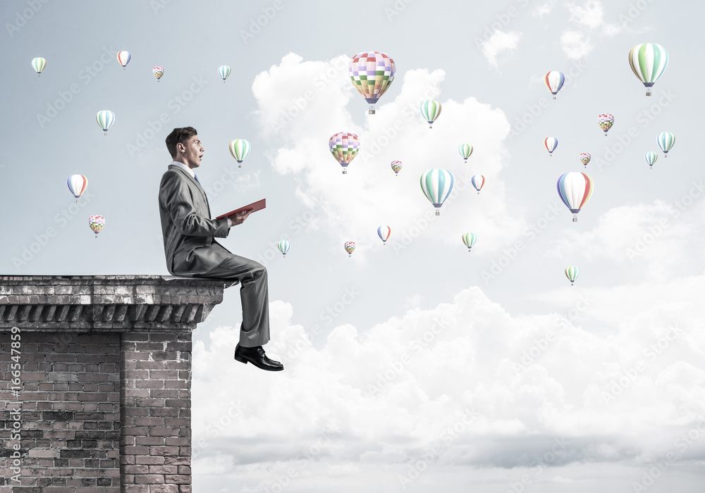 Man on roof reading book and aerostats flying in air Man on roof reading book and aerostats flying in air