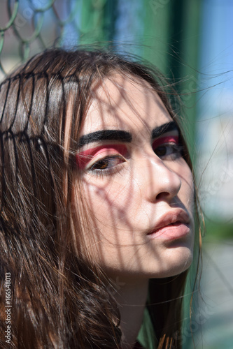 Portrait, young girl with a shadow in the form of a grid on flowing hair and the face