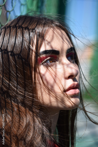 Portrait, young girl in profile with shadow in the form of a grid on flowing hair