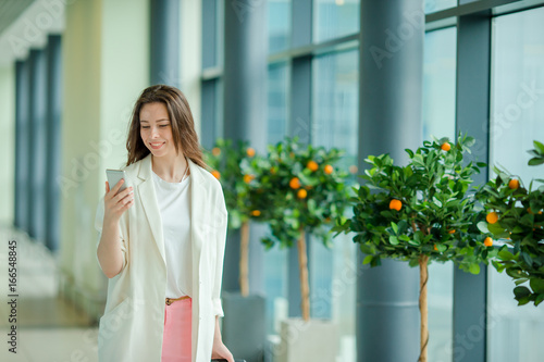 Portrait of young woman with smartphone in international airport. Airline passenger in an airport lounge waiting for flight aircraft photo