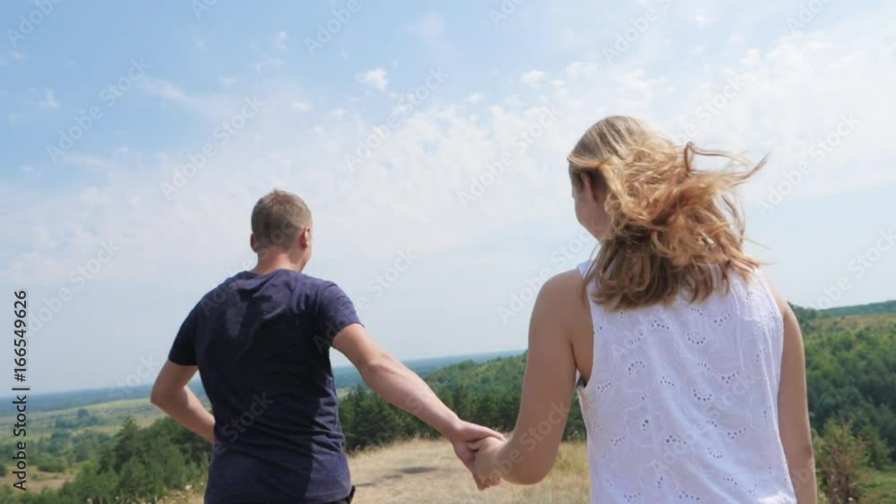 Slow Motion: A loving couple runs to the top, smiling, swirling together Slow Motion: A loving couple runs to the top, smiling, swirling together