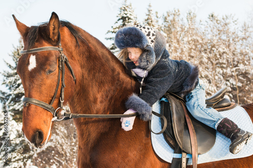 Small girl and horse in a winter