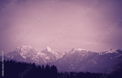 Photo depicting a beautiful moody frosty landscape. European alpine mountains with snow peaks on a blue sky background.