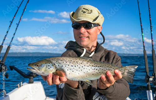 Fototapeta Naklejka Na Ścianę i Meble -  Happy angler with silver lake trout fishing trophy