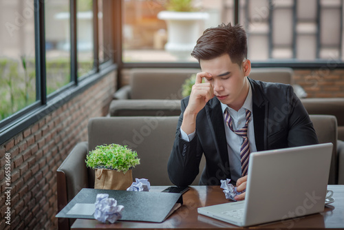 Portrait of an upset businessman at desk in office. Businessman being depressed by working in office. Young stressed business man feeling strain in eyes after working for long hours on compute