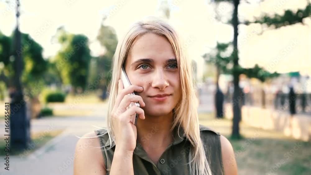 Pretty woman talking on her cell phone while she walks down the street. Pretty woman talking on her cell phone while she walks down the street.