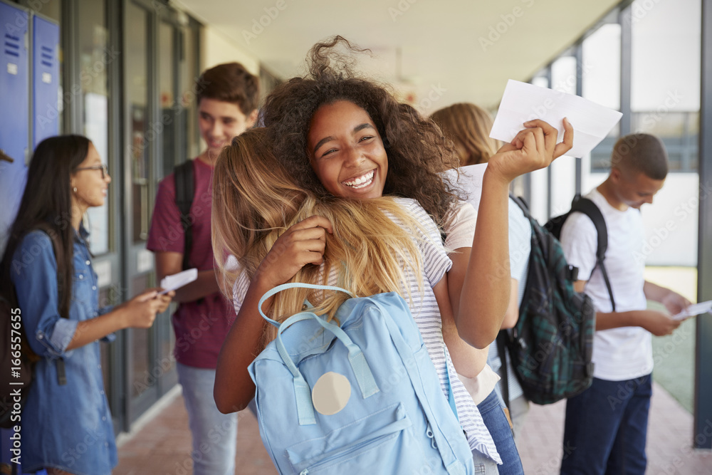 Two girls celebrating exam results in school corridor - obrazy, fototapety, plakaty 