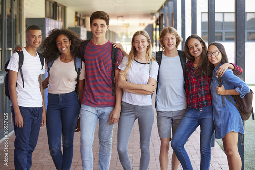 Teenage classmates standing in high school hallway photo