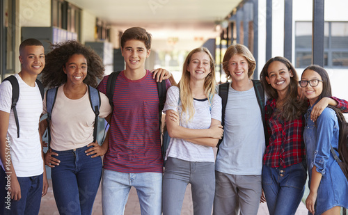 Teenage classmates standing in high school hallway photo