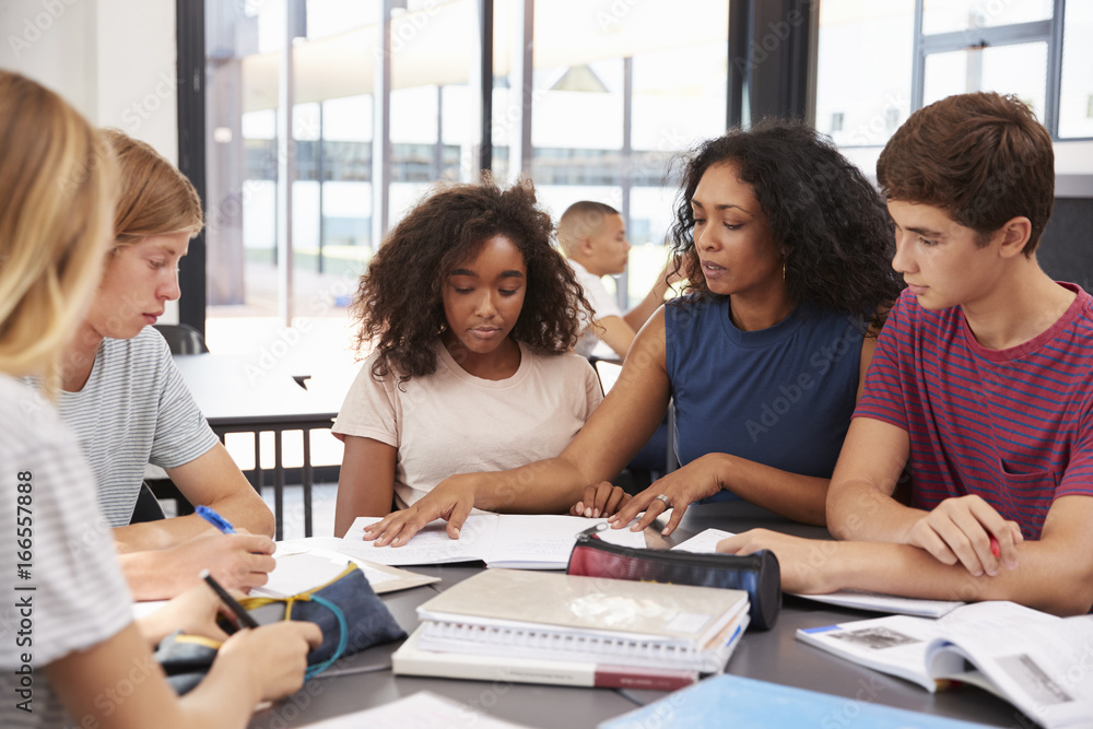 Fototapeta premium Teacher studying school books in class with high school kids
