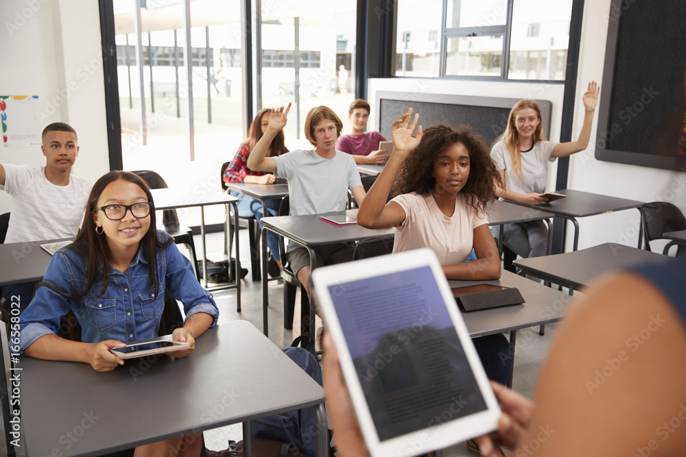 Teacher uses tablet in high school class, over shoulder view Teacher uses tablet in high school class, over shoulder view