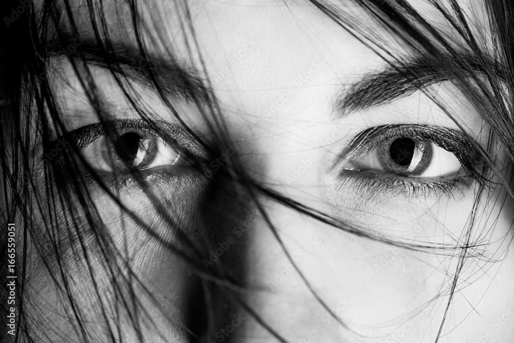 Fototapeta premium stared female eyes under blowing hair close up