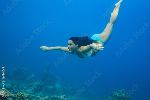 A brunette girl diving into blue sea water. Underwater photography of sport activity