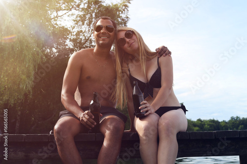 Young couple having a beer by a lake
