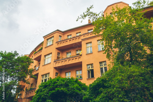 big and beautiful orange building with big balconies framed by trees