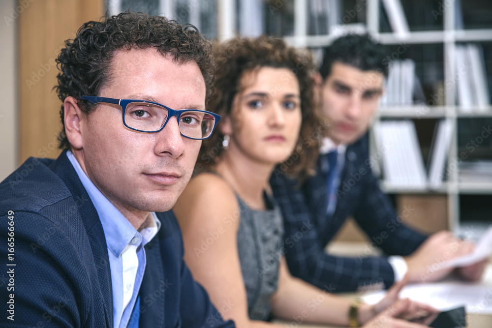 Close up of executive chief sitting at the negotiating table with his team in headquarters Close up of executive chief sitting at the negotiating table with his team in headquarters