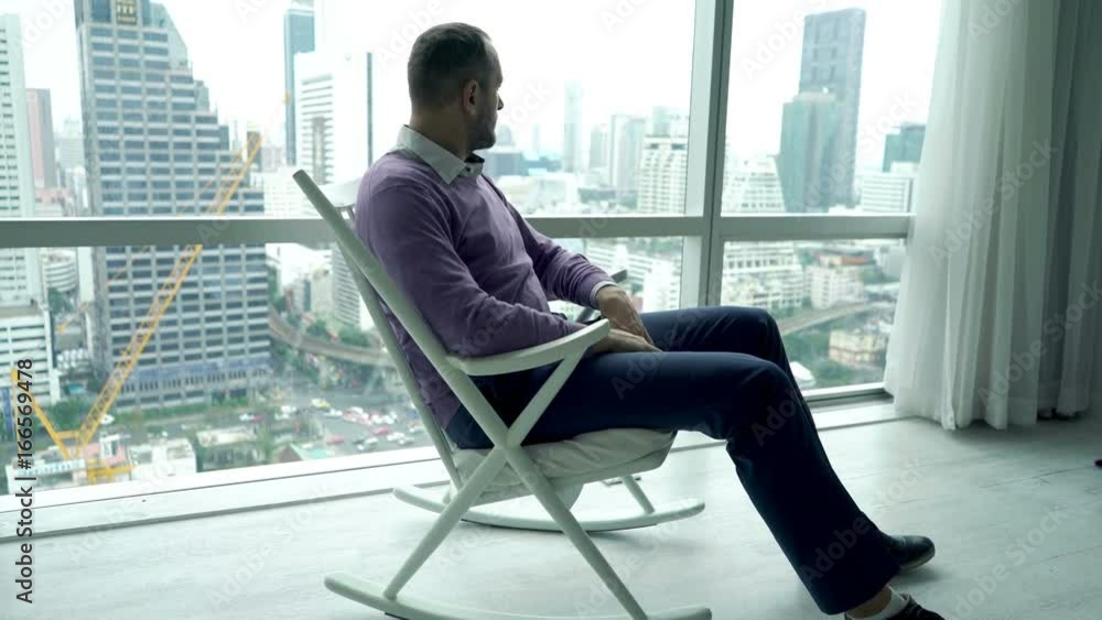 Young man relaxing and admire view form window sitting on rocking chair
Young man relaxing and admire view form window sitting on rocking chair