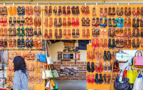 Fotografi A wall of leather sandals on display at the San Lorenzo market in Florence, Ital