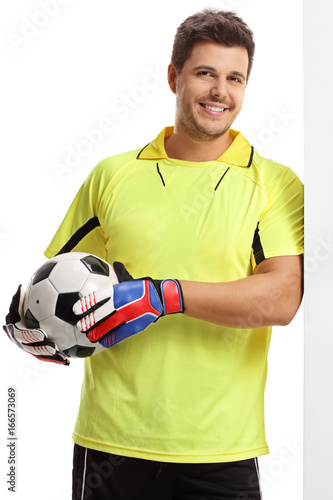 Goalkeeper with a football leaning against a wall