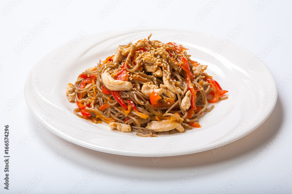 Italian pasta with chicken and peppers in a white plate on a light background