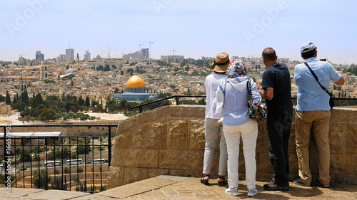 The guide shows the Jerusalem Old City view to the tourists and pilgrims. Mount of Olives is a famous Holy Land place and it has a fantastic view to the Old Jerusalem