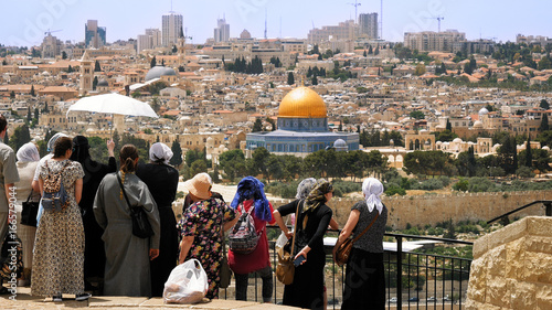 The Christian orthodox guide shows the Jerusalem Old City view to the pilgrims and tourists from the Mount of Olives. Famous Holy Land place and fantastic city view. photo