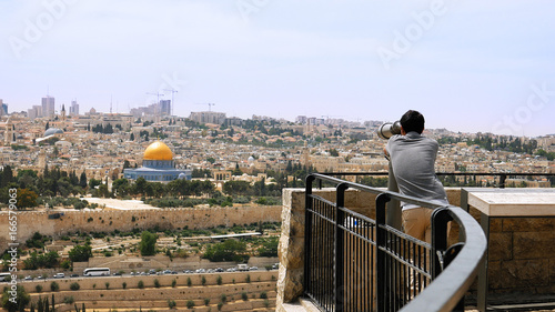 Tourist looks in binoculars tower viewer at the Jerusalem Old City view. Mount of Olives is a famous Holy Land place and it has a fantastic view to the Old Jerusalem