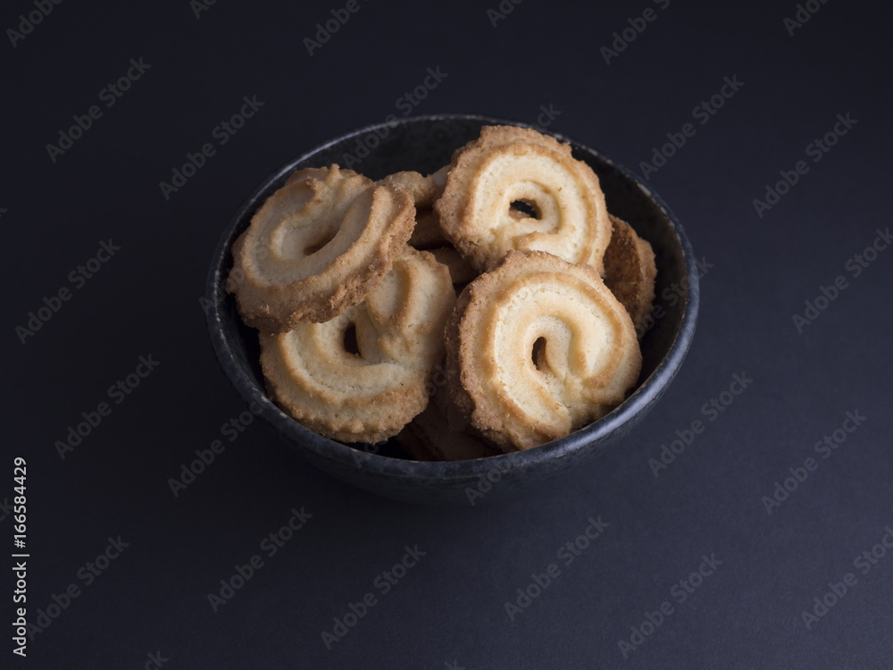 Danish vanilla wreaths cookies (vanillekranse) in black rustic bowl, isolated on black background Danish vanilla wreaths cookies (vanillekranse) in black rustic bowl, isolated on black background