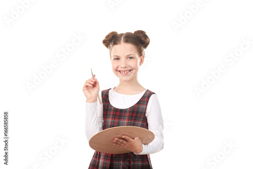 Portrait of cute girl in school uniform painting against white background