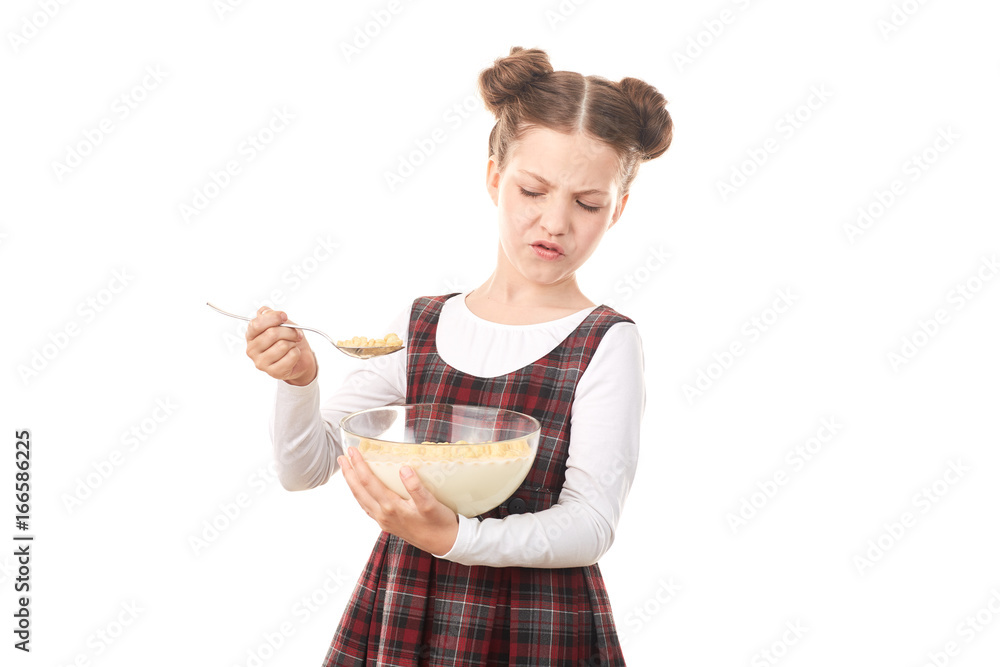 Portrait of cute girl in school uniform eating cereal with milk against white background Portrait of cute girl in school uniform eating cereal with milk against white background