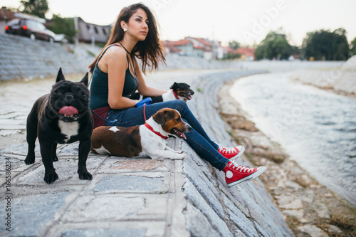 Photography Dog walker with dogs enjoying outdoors next to city river.