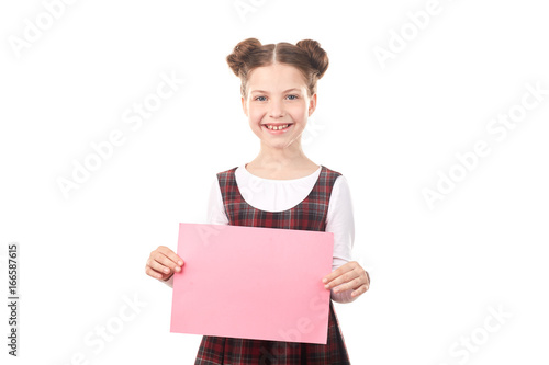 Portrait of smiling girl in school uniform holding blank paper against white background