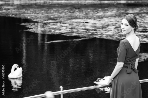 Fashionable model in garden. Pool with swan.