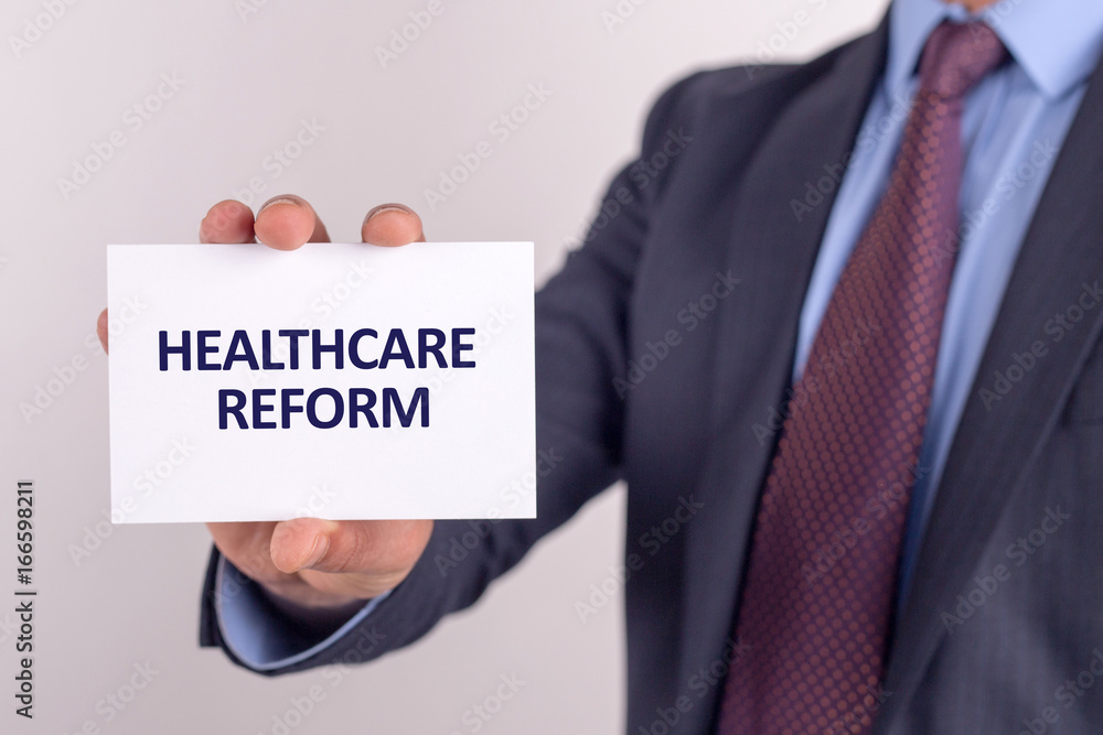Man showing paper with HEALTHCARE REFORM text Man showing paper with HEALTHCARE REFORM text