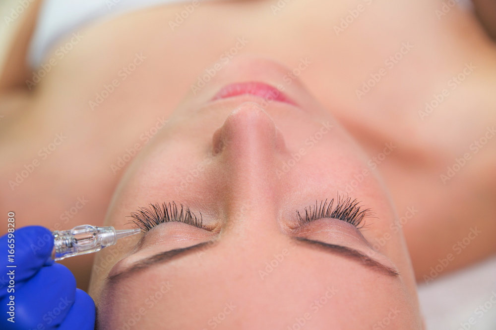 Beautiful young woman gets beauty injection in eye area