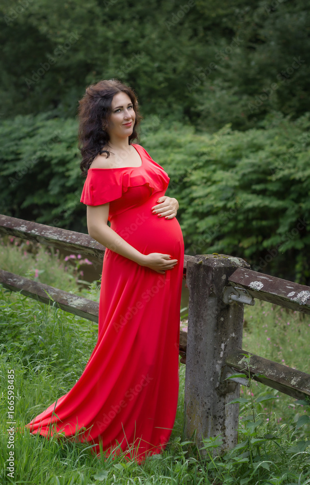 Pregnant woman in red dress in the park. Pregnant woman in red dress in the park.