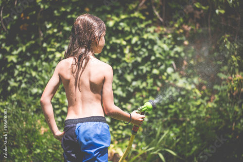 Boy watering the garden with a  hosepipe