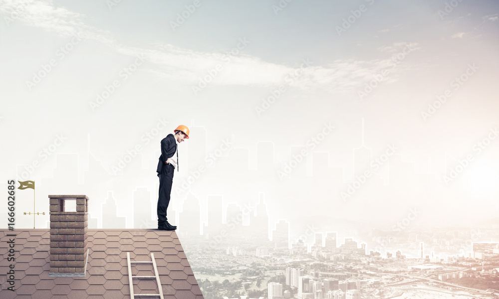 Engineer man standing on roof and looking down. Mixed media Engineer man standing on roof and looking down. Mixed media